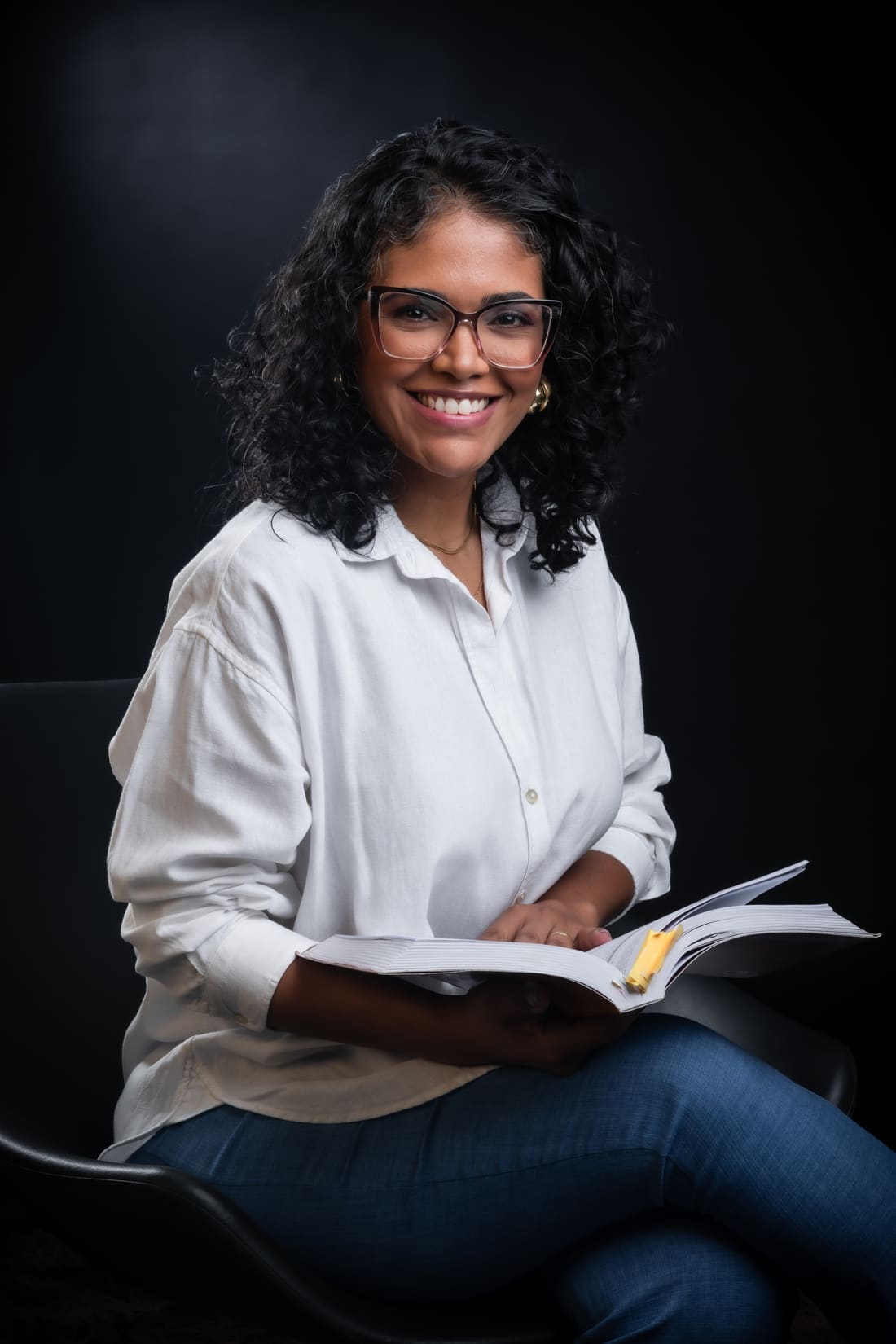 Jacqueline Porto, psicóloga e hipnoterapeuta, sorrindo com um livro em mãos
